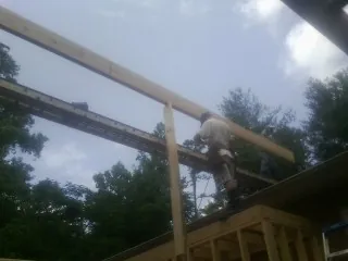 Carpenter setting a ridge beam over a new addition frame — Ice Dam Removal by Roofing Brothers in Balsam Grove