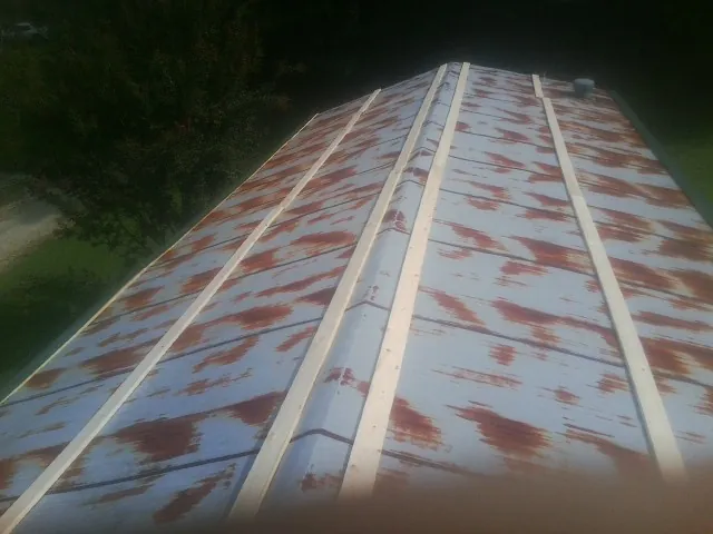 Rusted metal roof panels with new wood purlins before replacement — Storm Damage Roof Repair in Balsam Grove by Roofing Brothers