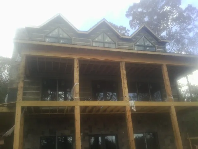 Dormers and porch framing on a large log home under construction — Roof Coating work by our crew in Balsam Grove