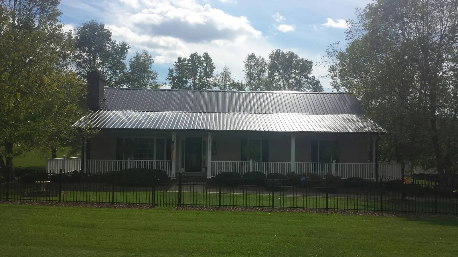 Gray metal roof on a brick ranch with a full width front porch — Gutter Guard Installation work by our crew in Balsam Grove