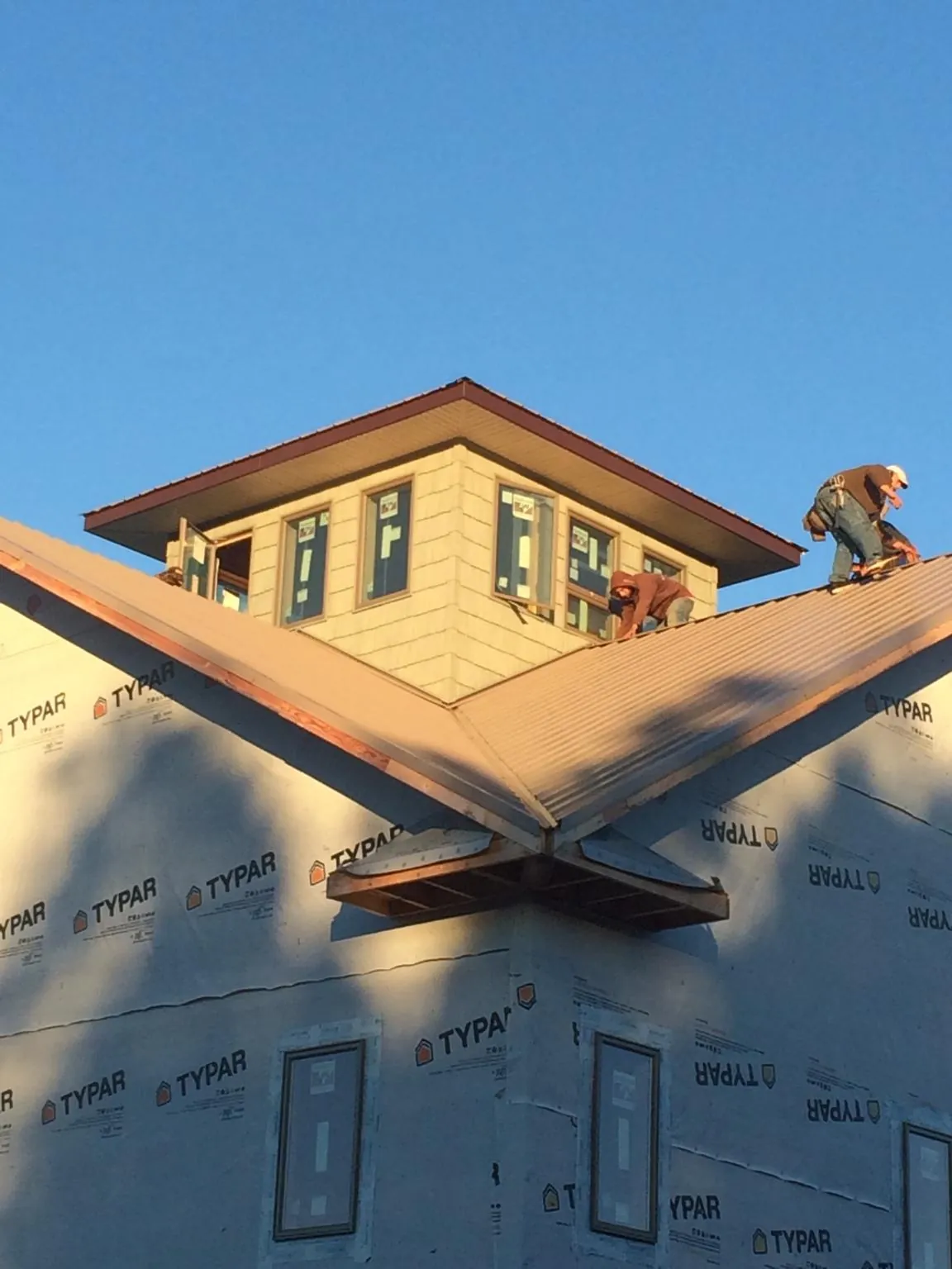 Roofers working around a rooftop cupola on a new metal roof at sunset — Roof Waterproofing in Balsam Grove by Roofing Brothers